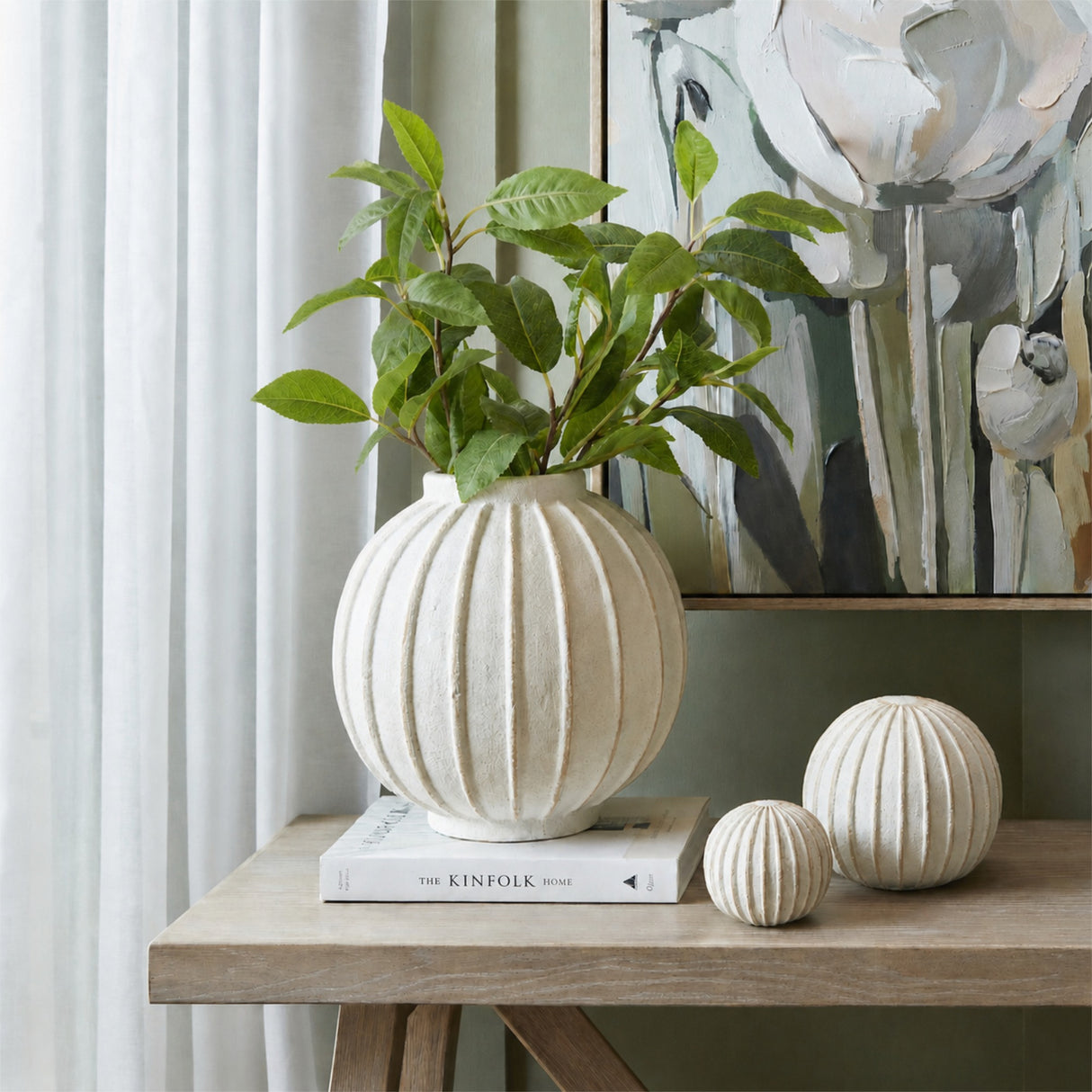 Hill Interiors Laurel Leaf Spray arranged in a ribbed white spherical vase on a console table, styled with matching decorative balls and floral artwork.