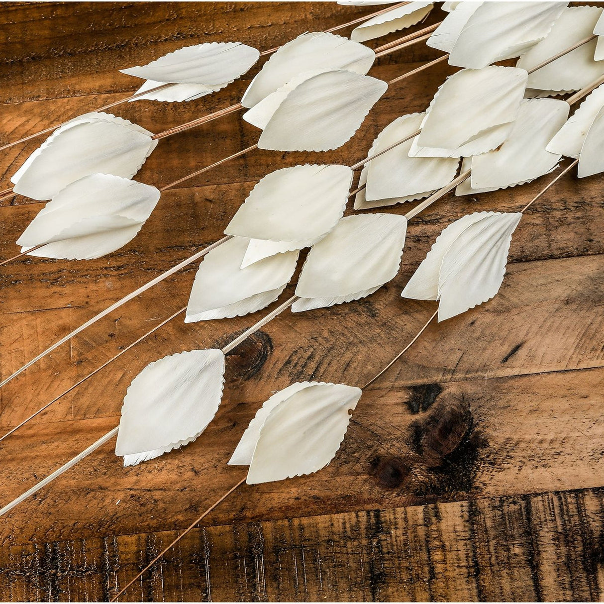 Hill Interiors Bouquet of Dried Thlaspi Arvense faux stems with white coin-shaped seed pods along slender branches, displayed on a rustic wooden surface.