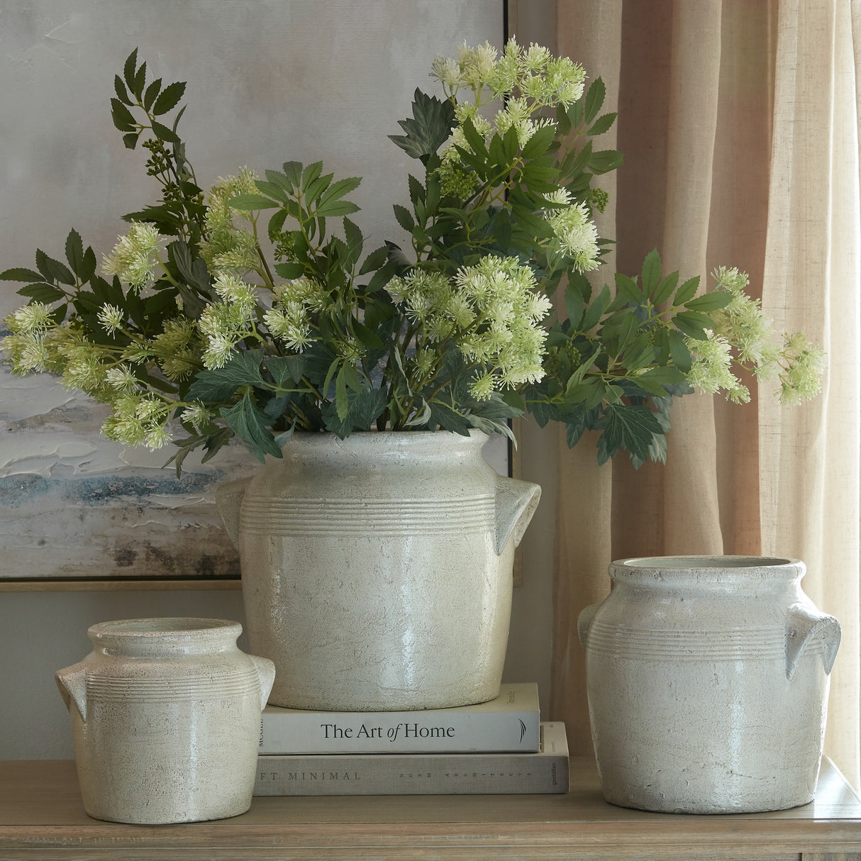 Hill Interiors Long Fennel Stems with feathery green and cream plumes arranged in a rustic stone pot, styled with books beside two smaller ceramic jars.