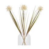 Three Hill Interiors cream aster spider chrysanthemum faux stems with spiky petals and long green grass-like leaves arranged in a clear glass vase.