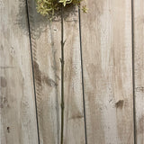 Hill Interiors Green and Beige Allium faux stem showing the slender upright plastic stem and globe floret head against pale wooden planks.
