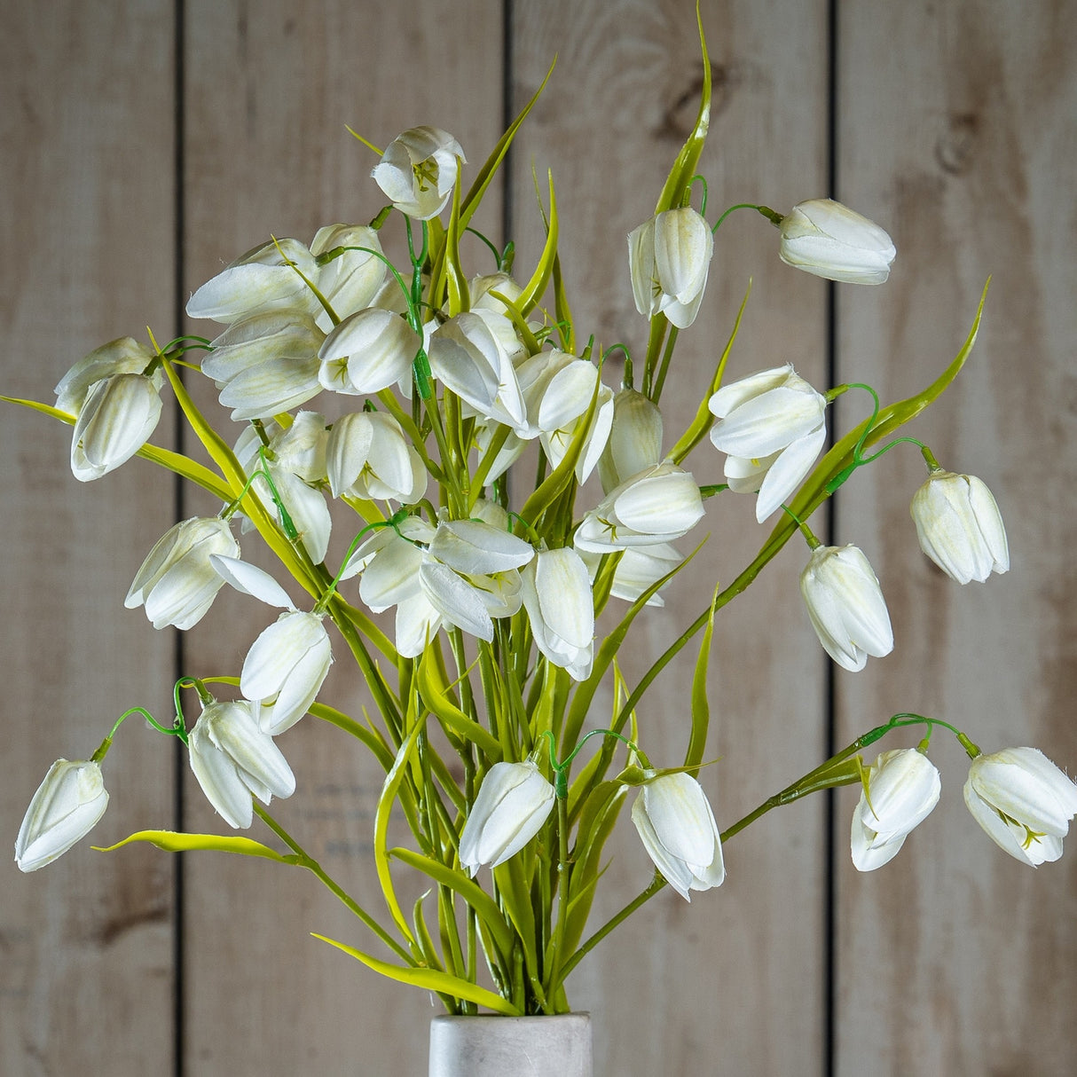 Hill Interiors White Fritillaria faux flower stem with nodding cream bell-shaped blooms and slim green foliage, displayed against a wooden plank background.