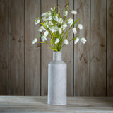 Hill Interiors White Fritillaria Stem with nodding bell-shaped blooms and slim green foliage arranged in a tall grey stone bottle vase against wood panelling.