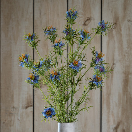 Hill Interiors Purple Nigella Love In A Mist faux flower stems with blue-purple blooms and feathery green foliage in a pale vase against wood panelling.
