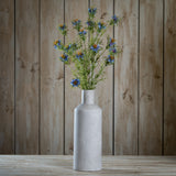 Hill Interiors Purple Nigella Love In A Mist faux stems with feathery bracts arranged in a tall grey stone bottle vase against wood panelling.