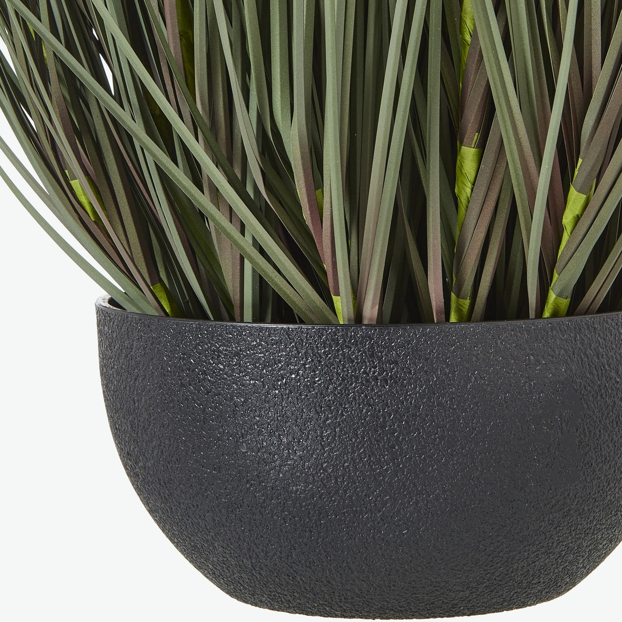 Close-up of Hill Interiors Large Fountain Grass faux plant, showing slender green and brown blades set in a textured matte black pot.
