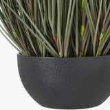 Close-up of Hill Interiors Large Fountain Grass faux plant, showing slender green and brown blades set in a textured matte black pot.