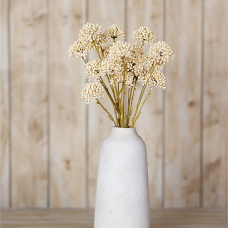 Hill Interiors Cream Allium Spray with clustered globe-like florets on slim stems, arranged in a tall white ceramic vase against a light wood panel backdrop.