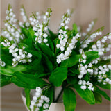 Close-up of Hill Interiors Lily of the Valley Bunch faux plant, showing tiny white bell-shaped blooms on slim stems arching above bright green leaves.