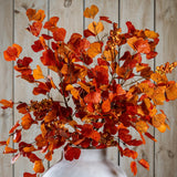 Hill Interiors Large Autumn Spray with Berries in a stone vase, showing layered orange and red foliage with berry clusters against a wooden plank backdrop.
