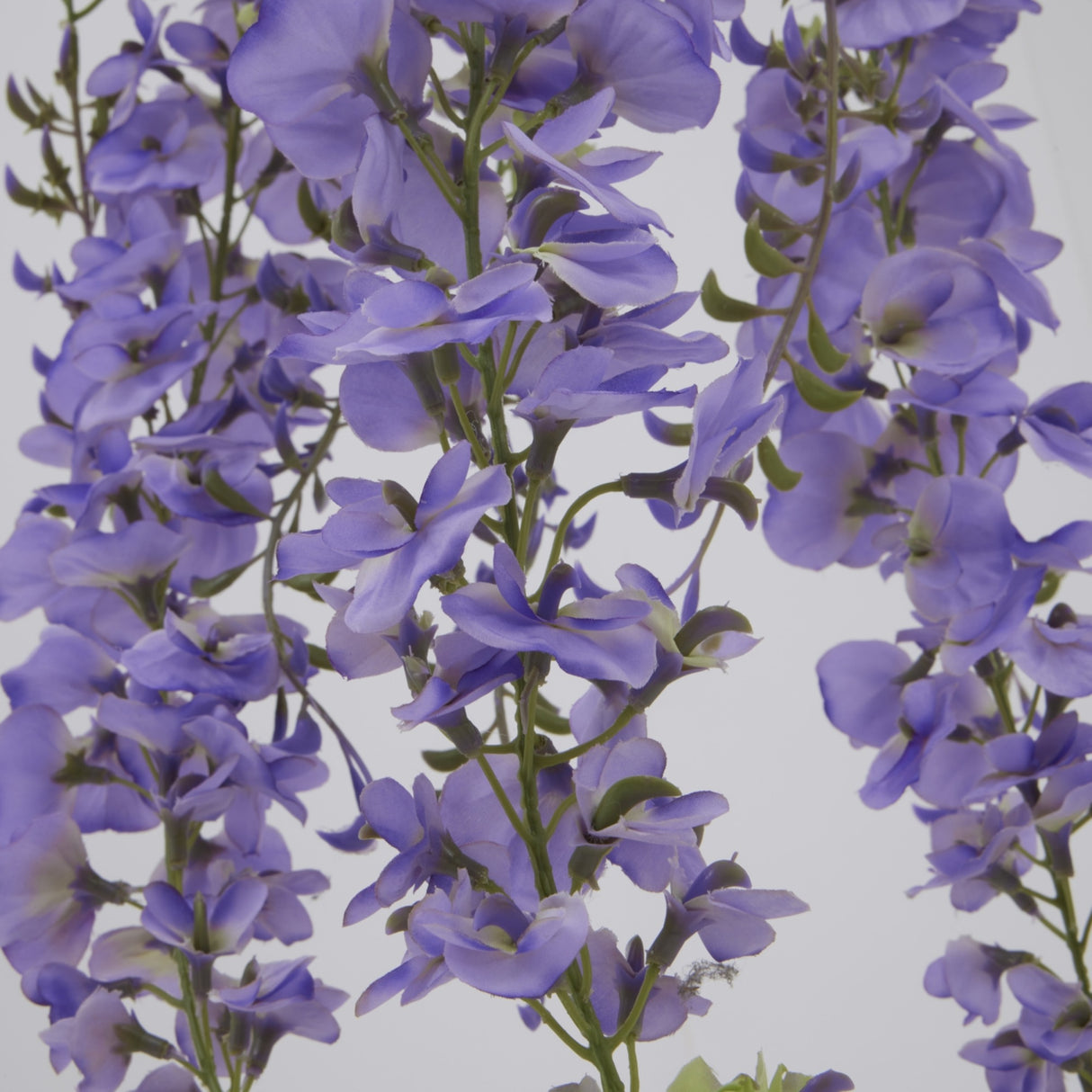 Close-up of Hill Interiors Large Purple Wisteria Spray showing cascading clusters of ruffled lilac blooms and small green leaves along trailing stems.
