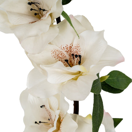 Close-up of the Hill Interiors White Bloom Large Spray faux flower stem, showing layered white petals with speckled centres, dark stamens, and green leaves.
