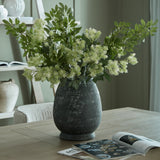 Hill Interiors Green French Meadow Spray arranged in a distressed dark grey ceramic vase on a wooden table, styled with an open magazine in a living room.