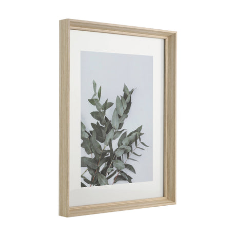Renabie Photo Frame 32.5 x 42.5cm in oak effect wood with white mount, shown at an angle displaying a leafy green plant print against a plain white background.