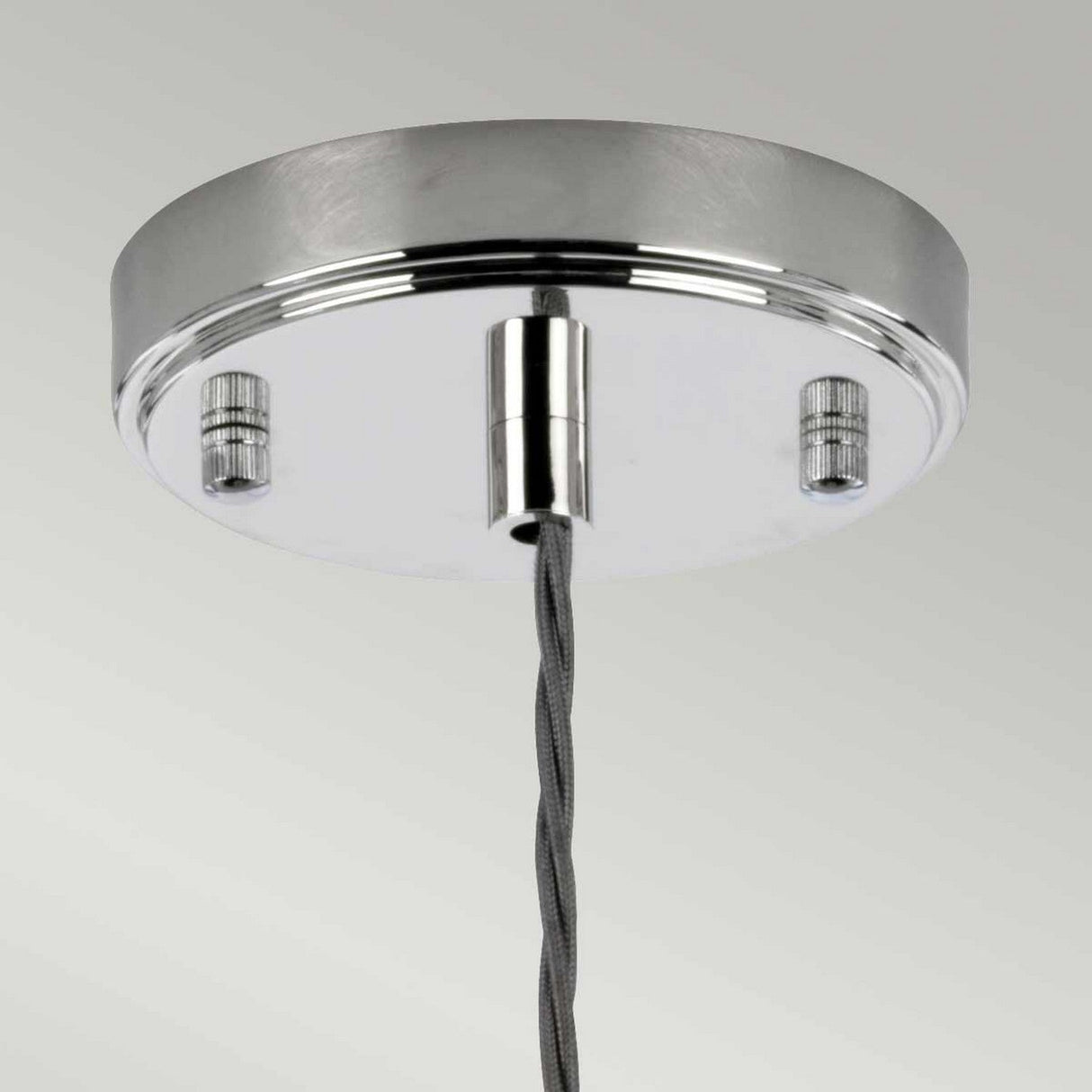 Close-up of the Reno 1 Light Pendant in polished nickel with a smoke glass shade and metal canopy. A twisted grey cord extends from the center, connecting to a lamp holder for the pendant light. The background is a plain, light grey.
