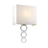 The Ria Medium 1 Light Wall Light in polished chrome features a sleek design with a faux silk, white rectangular shade and a base of three interconnected hexagonal shapes, providing a softly illuminated glow that accentuates its geometric elegance.