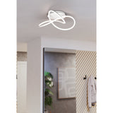 Riaza LED Ceiling Light in white, featuring looped ribbon-style arms on a round canopy, shown illuminated on a hallway ceiling above a mirror and coat hooks.