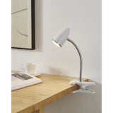 Riccio 1 Clip On Lamp in white and chrome, with a cone-shaped shade on a flexible gooseneck, clipped to a wooden desk edge in a study setting.