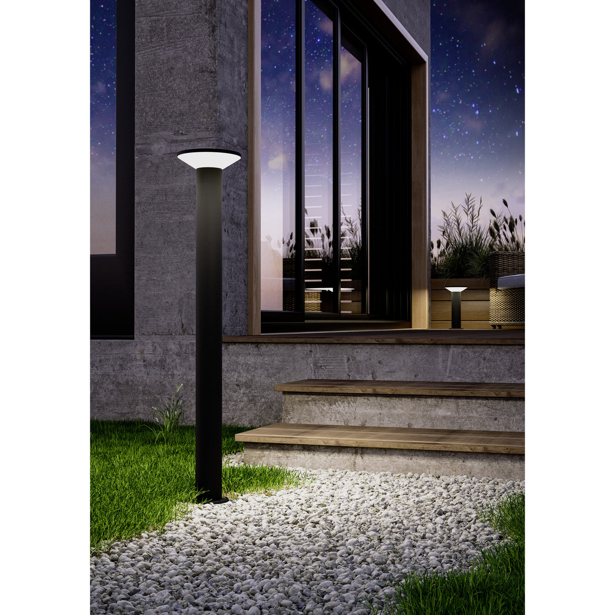 Rigosa Outdoor LED Floor Lamp in black, slim steel post with flat disc cap over a white diffuser, shown illuminated beside steps on a gravel path at night.