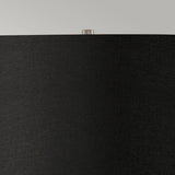Close-up of the Ripple 1 Light Table Lamp featuring a sleek black shade and a small metallic finial on top, perfectly complementing its black base. This piece epitomizes contemporary lighting against the backdrop of a light gray wall, showcasing minimalist design at its finest.