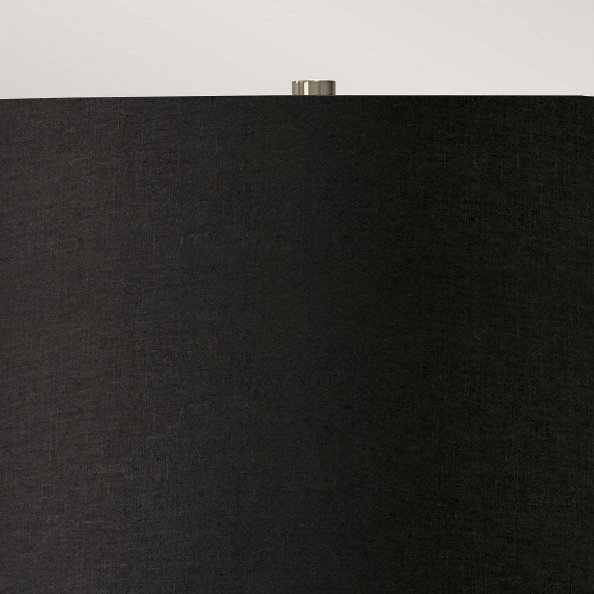 Close-up of the Ripple 1 Light Table Lamp featuring a black shade with a slightly textured surface. The top of this modern lamp showcases a small, metallic finial against a neutral background, blending seamlessly into your contemporary lighting setup.