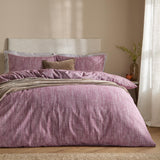 Harris Cotton Herringbone Duvet Cover Set in beetroot on a bed with striped pillowcases and a taupe throw, set against a neutral bedroom wall.