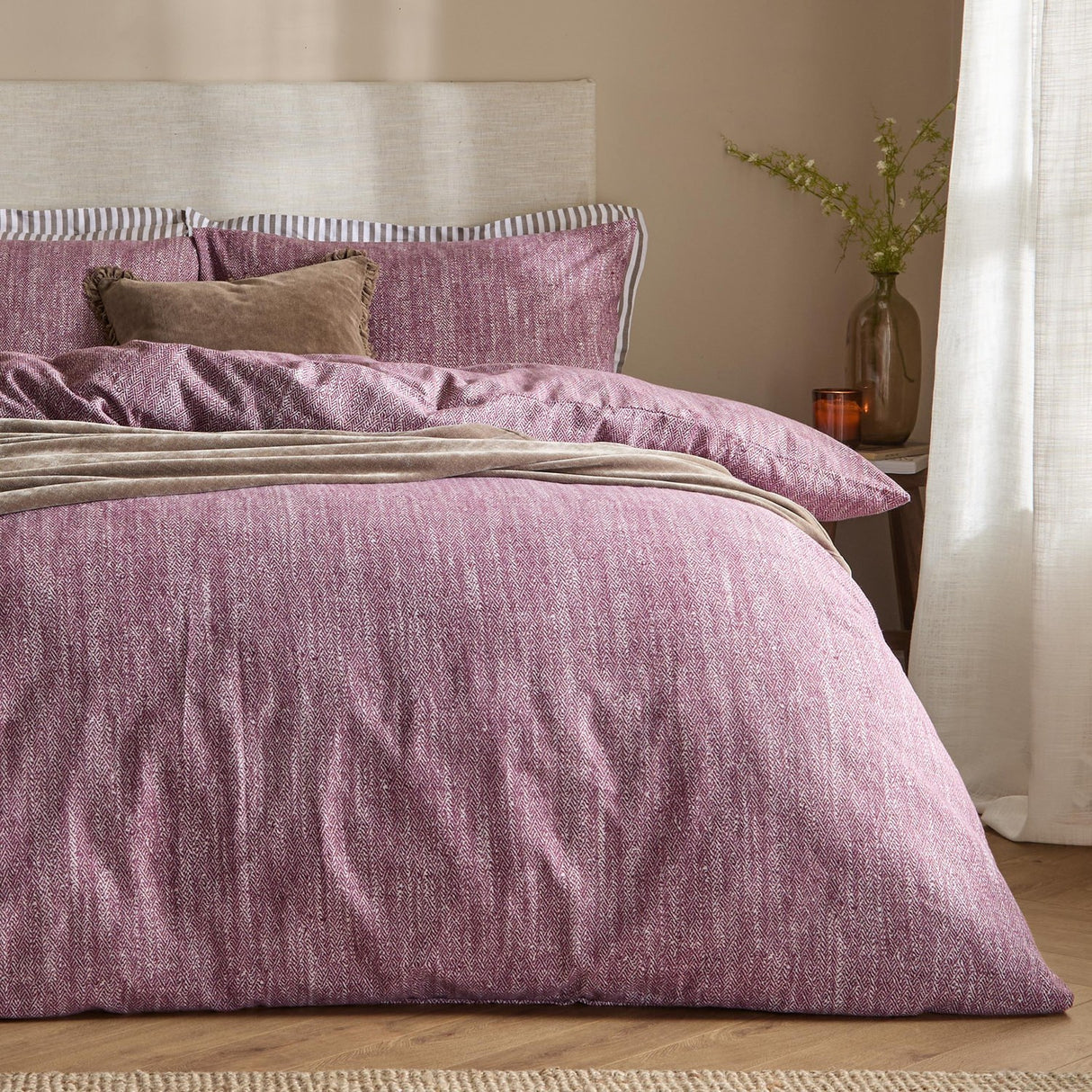 Harris Cotton Herringbone Duvet Cover Set in beetroot on a bedroom bed, showing brushed cotton fabric with subtle chevron texture, striped pillow edge, and a beige upholstered headboard.