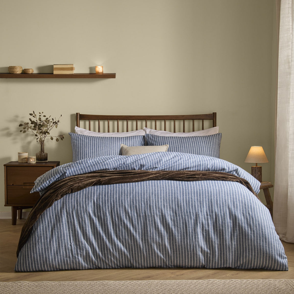 Holme Stripe Cotton Brushed Duvet Cover Set in denim blue with white pinstripes, styled on a bed with matching pillowcases, a cushion, and a draped throw in a bedroom setting.