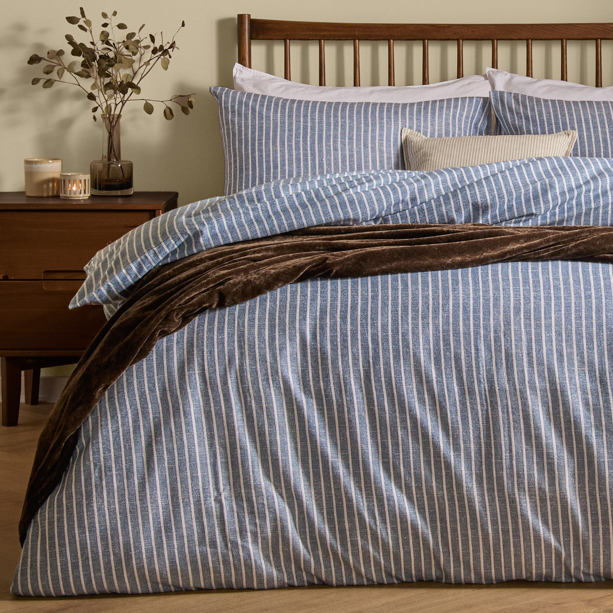 Holme Stripe Cotton Brushed Duvet Cover Set in denim blue and white on a bed with matching pillowcases, styled with a brown throw in a bedroom setting.