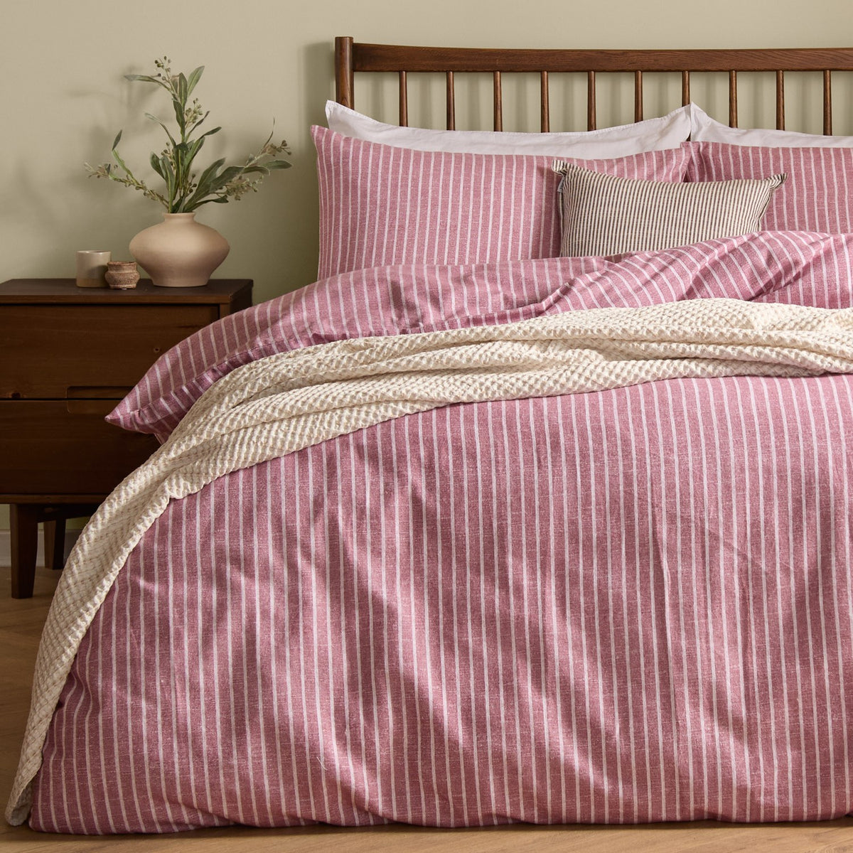 Holme Stripe Cotton Brushed Duvet Cover Set in Rosewood, a pink and white striped duvet with matching pillowcases on a bed with a dark wood headboard, styled with a cream throw in a bedroom setting.