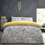 Doodles Polycotton Printed Duvet Cover Set in white/black with dense black doodle print, reversible to yellow, shown on a bed with matching pillowcases in a bedroom setting.