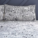 Doodles Polycotton Printed Duvet Cover Set in white/black, pillowcases and duvet covered edge-to-edge with black line-art doodles of aliens, skulls and speech bubbles, shown on a bed.