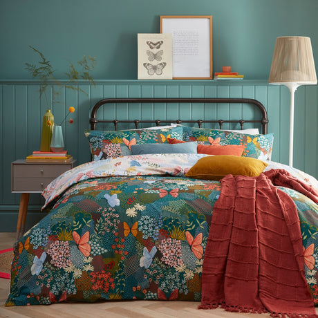 Forage Printed Floral Duvet Cover Set in Teal on a bed with coordinating pillowcases and a rust-red throw, set against teal panelled bedroom walls.