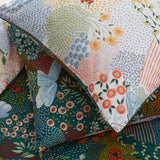 Forage Printed Floral Duvet Cover Set in teal, close-up of pillowcase corner showing patchwork-style floral, butterfly and dot print in coral, blue, amber and green on a deep teal ground.