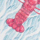 Close-up of the Abersoch Abstract Polyester Placemat in Marine, showing a coral-red lobster tail motif on a woven blue and white coastal-patterned fabric.