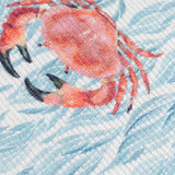 Close-up of the Abersoch Abstract Polyester Table Runner in Marine, showing woven fabric printed with a pink crab design on an abstract blue coastal background.