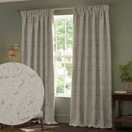 Acanthus Jacquard Linen pencil pleat curtains in beige with ivory-cream leaf pattern, hung at a living room window, with a fabric texture close-up inset.
