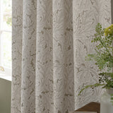 Acanthus Jacquard Linen Pencil Pleat Curtains in beige with ivory-cream woven leaf pattern, shown gathered by a window near a potted plant.