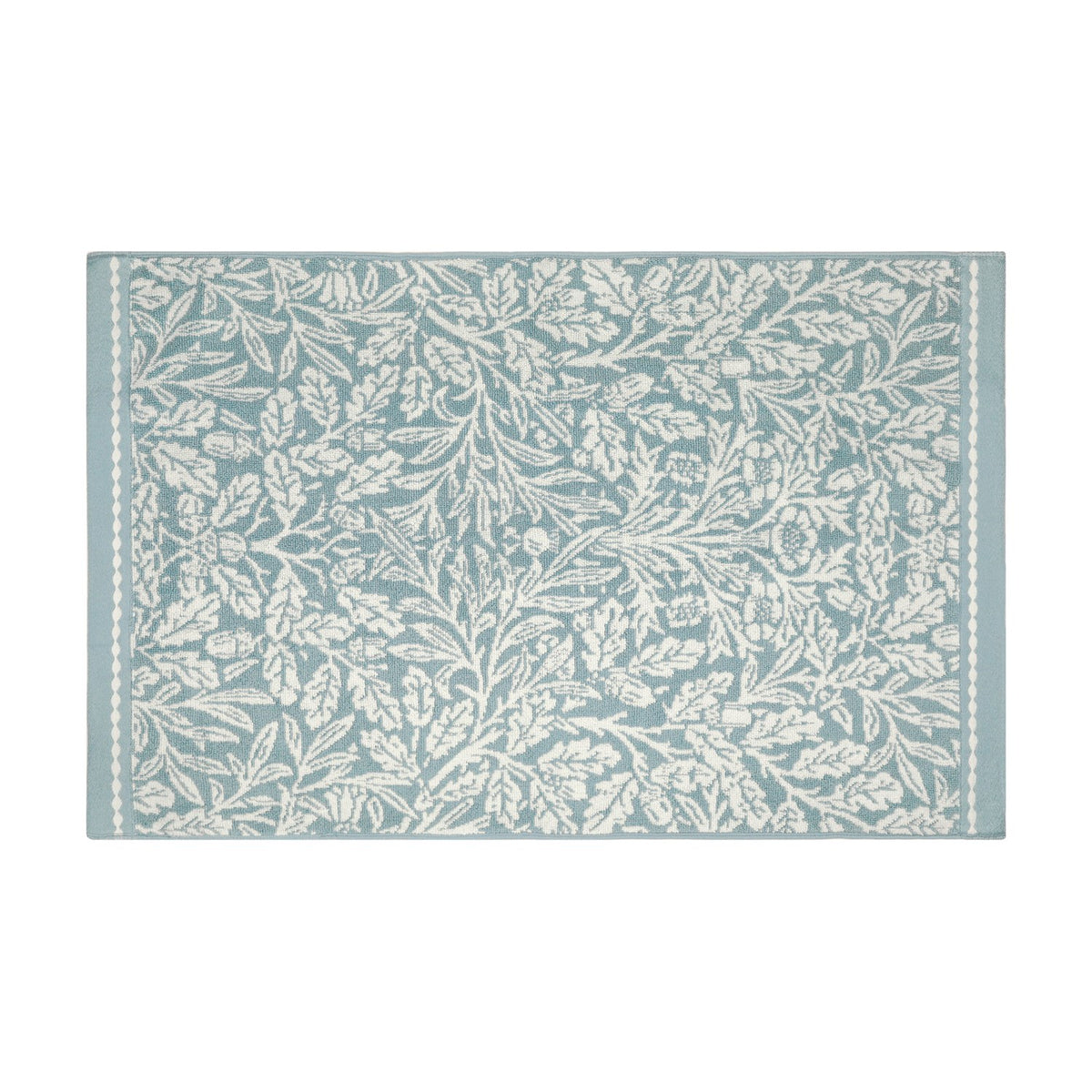 Rectangular cotton bath mat in mineral blue with an all-over off-white Acorn floral and foliage pattern, framed by slim beaded side borders, on a plain white background.