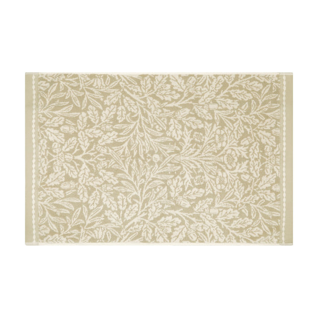 Acorn Floral Cotton Bath Mat in natural beige and cream, woven with a trailing Morris acorn and oak leaf pattern with slim side borders, shown on a plain white background.