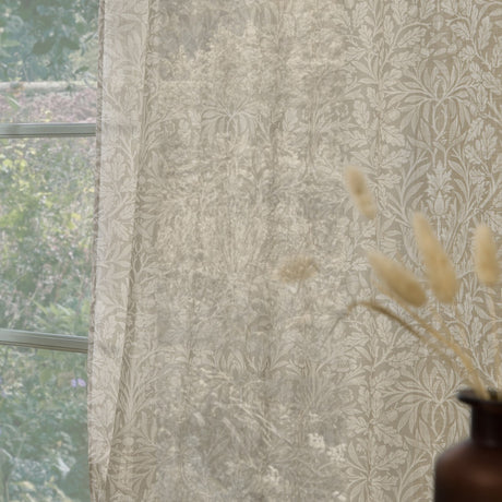 Acorn Damask Linen Curtain Panel in natural cream tones, semi-sheer with a leaf and acorn print, shown hanging at a window beside dried grasses.