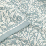 Close-up of Acorn Jacquard Cotton Towels in mineral blue, showing woven acorn and foliage pattern with a scalloped-edge cream border trim.