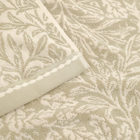 Close-up of an Acorn Jacquard Cotton Towel in natural beige, showing the woven acorn and oak-leaf pattern with a scalloped braid border.