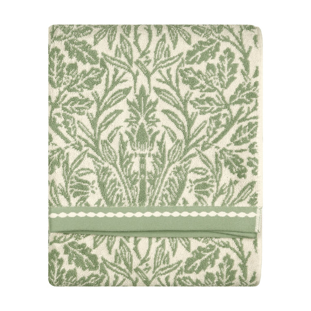 Folded cotton towel with sage green acorn and foliage jacquard pattern on cream, banded trim edge, shown on a plain white background.