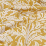Close-up of the Acorn Tonal Jacquard Cotton Blend Throw in gold, showing draped folds with a woven cream leaf and acorn pattern.