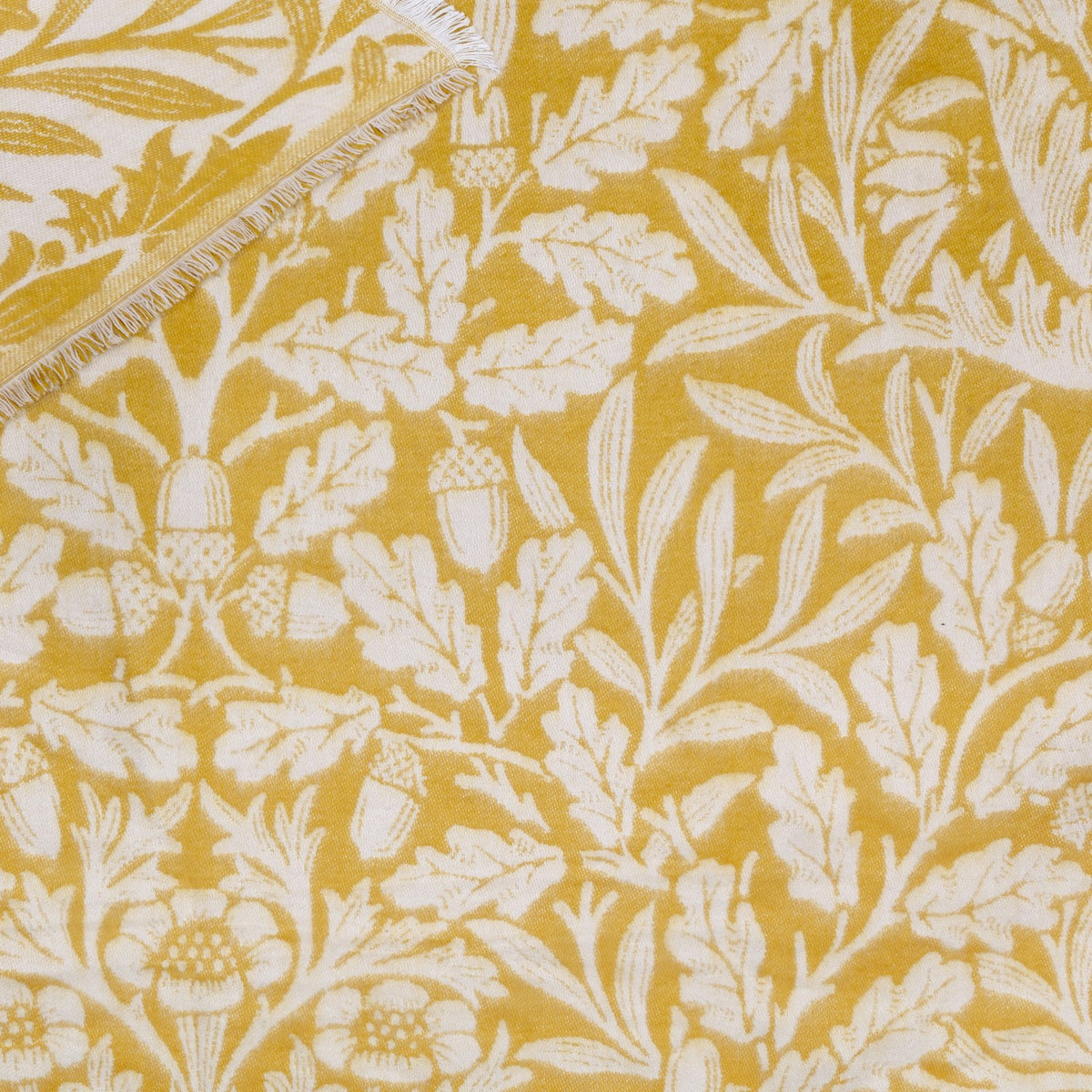 Acorn Tonal Jacquard Cotton Blend Throw in gold and cream, woven with an Acorn oak leaf and acorn pattern and finished with a short fringed edge.