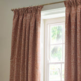Acorn Tonal Jacquard pencil pleat curtains in brick, woven acorn branch pattern in pale cream, framing a window in a light-toned room.