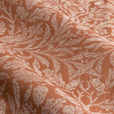 Close-up of Acorn pencil pleat curtain fabric in brick, showing a jacquard woven acorn and leaf pattern in pale cream on a rust polyester ground with soft draped folds.