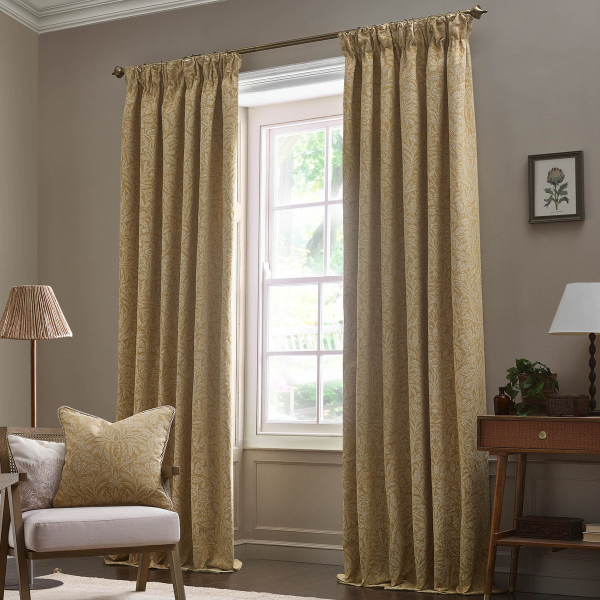 Saffron-gold pencil pleat curtains with tonal Acorn jacquard pattern hang from a bronze pole beside a window in a living room setting.