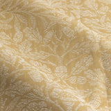 Close-up of Acorn Tonal Jacquard pencil pleat curtain fabric in saffron-gold, showing woven acorn and branch pattern in soft tonal relief across polyester cloth folds.